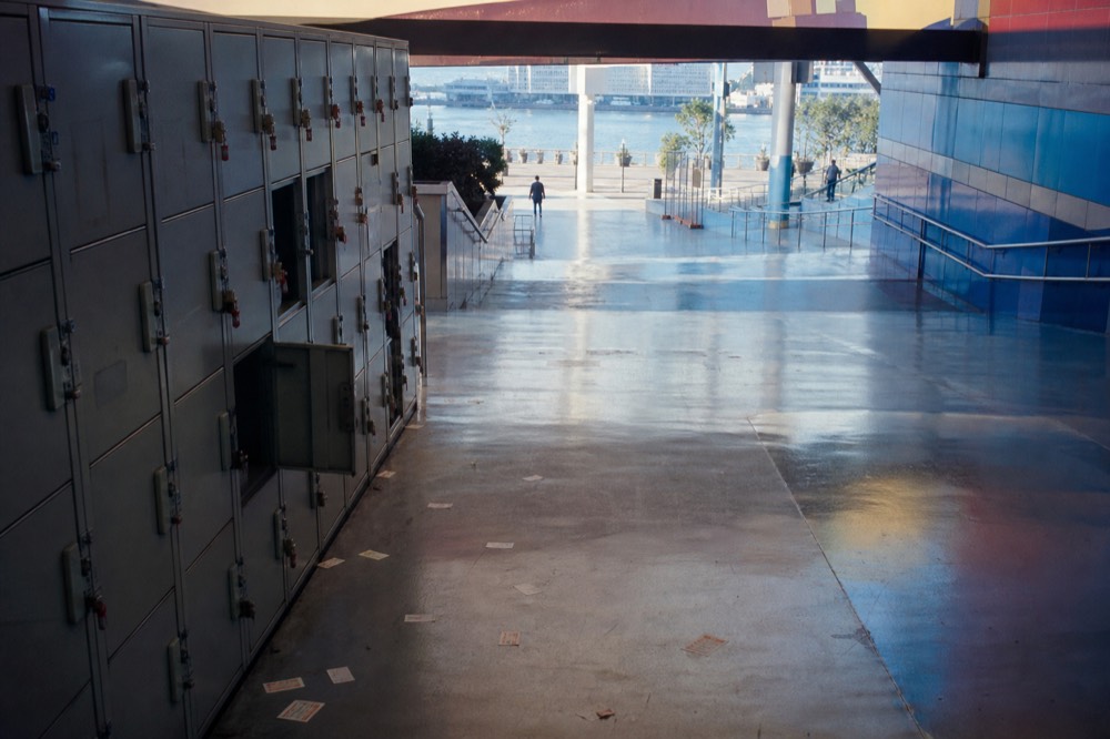 Coin lockers and a wide sloping walkway inside an aquarium entrance hall with soft blue light