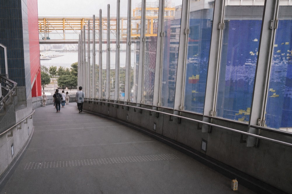A wide sloped ramp curving down around a tall blue aquarium tank seen through tall glass walls