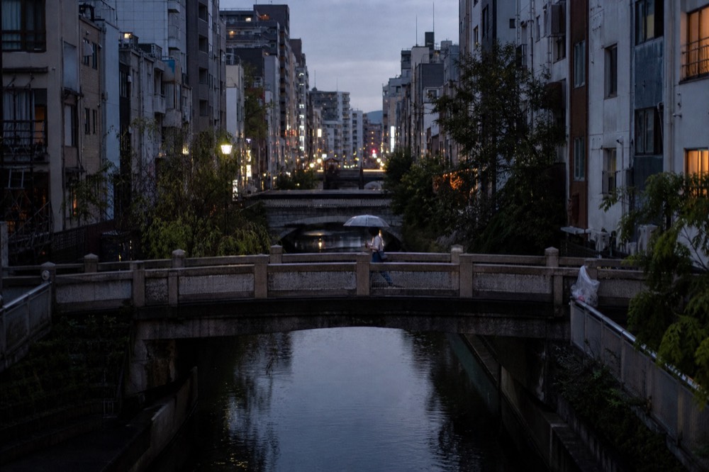 Osaka city street scene with a canal, bridges and illuminated signboards along the water at dusk