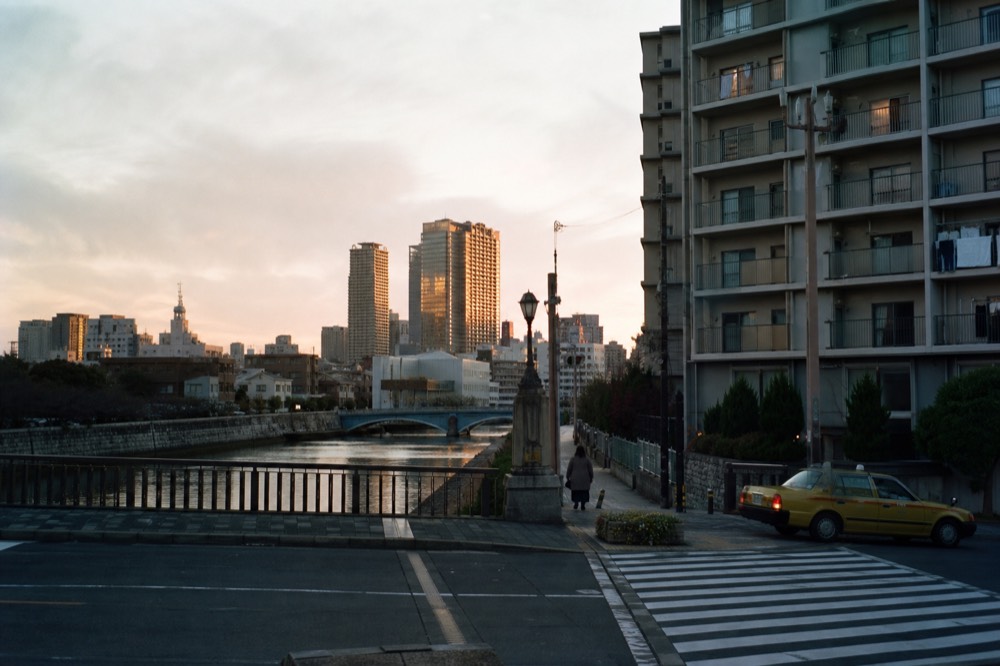 Wide Osaka cityscape at dusk with river bridges and the harbour district in the distance