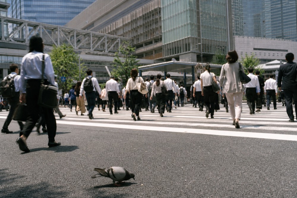 A busy pedestrian crossing outside a large rail station complex in northern Osaka