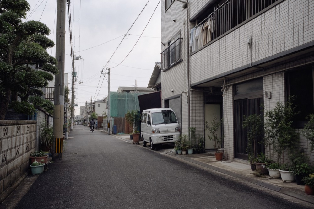 Quiet residential street near the Osaka Bay waterfront with low buildings and parked bicycles