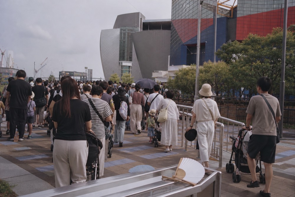 Crowd of visitors with strollers waiting at an aquarium entrance during a busy afternoon