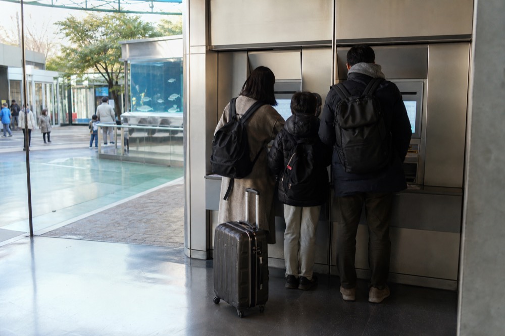 A family reading the ticket machines and price calendar at the aquarium entrance