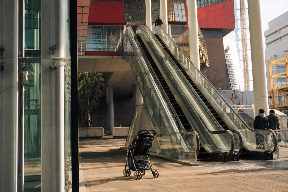 Long escalator rising through a glass atrium toward the aquarium entrance