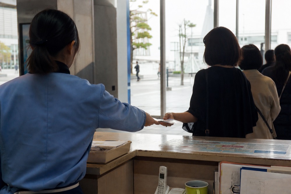 Information desk with a staff member handing a brochure to a visitor