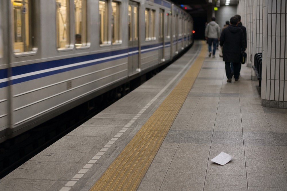 Subway platform with a departing train and overhead route signs