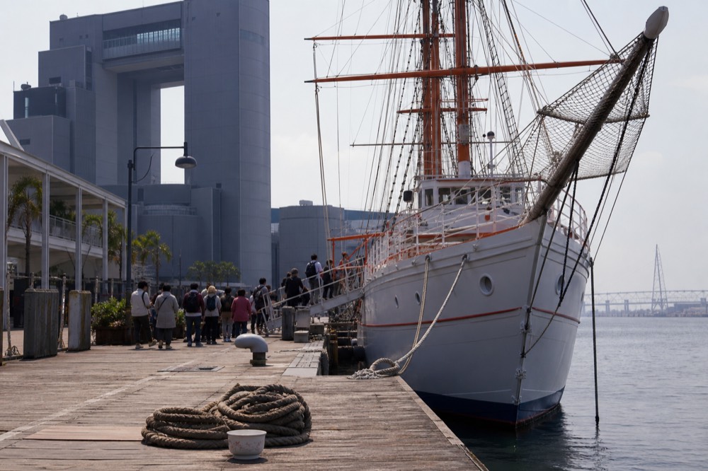 Replica sailing ship moored at a harbor wharf with visitors boarding