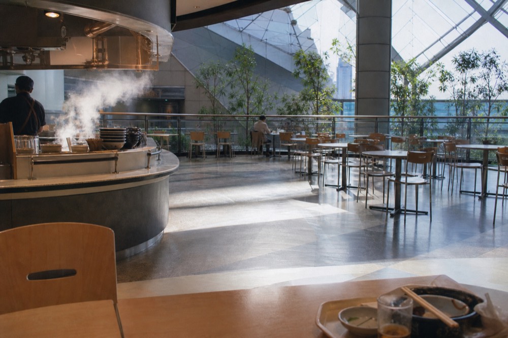 Shopping mall interior with a food counter and seating area on an upper floor